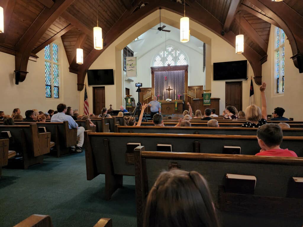 people sitting on chair in front of table while holding pens during daytime
